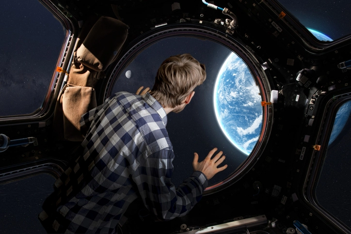 A young man inside a space capsule looking down at earth from outer space