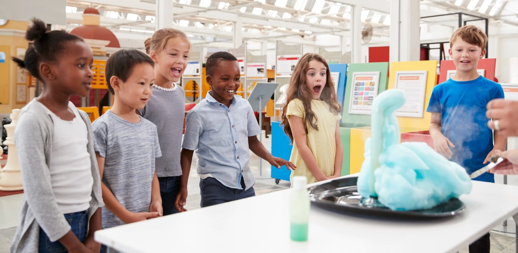 Excited kids looking at a science experiment of blue foam coming out of a lab glass