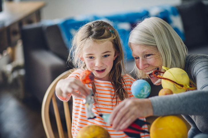 Elderly woman and a young girl smiling and looking at miniature planets