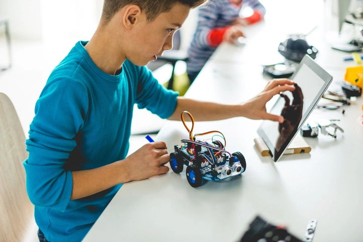 Young boy working on a small electric toy car with an ipad