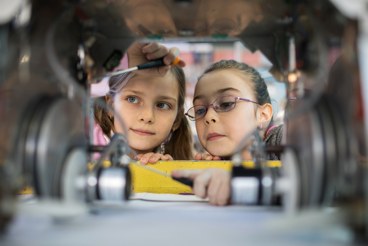 Two girls focused and building a machine